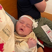 Hannelore joined the competition — help win amazing prizes! arm, baby, casual_clothes, closeup, clothing, comfort, fabric, flower, hand, headband, indoor, infant, peaceful, person, relaxation, resting, sleeping, soft_lighting, tag, wooden_bench