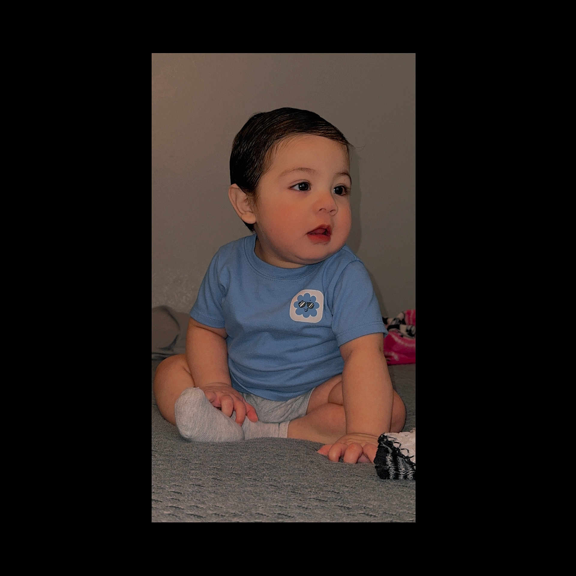 Jose Jr is registered to the contest to win money with this photo: baby, blue_shirt, child, cross_legged, curly_hair, cute, expression, floor, foot, hand, indoor, looking_away, portrait, short_sleeves, sitting, skin, sock, toddler, wall, young_child