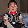 baby, child, toddler, boy, face, clothing, bow_tie, vest, pants, socks, bed, blanket, doll, indoor, portrait, cute, expression, sitting, person, furniture