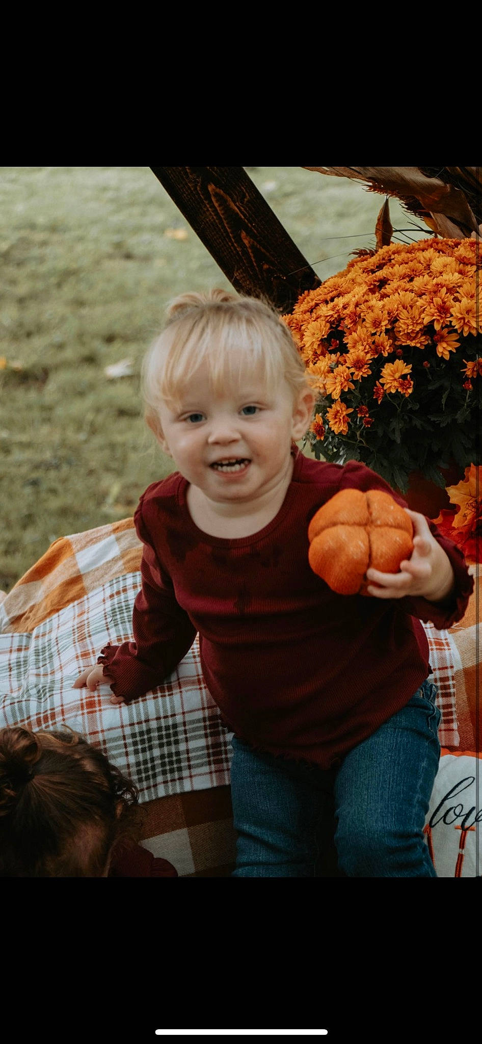 Kalani is registered to the contest to win money with this photo: baby, child, event, flower, fun, gesture, grass, hairstyle, happy, jeans, joy, leisure, people_in_nature, person, plaid, plant, sitting, smile, tartan, toddler