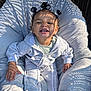 toddler, child, smiling, hair_buns, sunlight, shadow_pattern, cushion, chair, outdoor, casual_clothing, hoodie, pants, happy, cute, person, baby, relaxing, daylight, portrait, seat