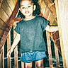 Milaní joined the competition — help win amazing prizes! child, curly_hair, tshirt, denim_shorts, crocs, pink_socks, wooden_structure, playground, outdoor, daylight, smiling, person, standing, wood, play, young_child, casual_clothing, fun, exploration, candid