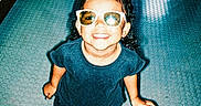 Milaní is registered to the contest to win money with this photo: child, girl, sunglasses, smile, happy, standing, blue_dress, curly_hair, indoor, floor, playful, cute, fashion, portrait, person, shoes, bright, light, shadow, fun
