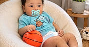 Mason is registered to the contest to win money with this photo: baby, basketball, carpet, chair, child, cozy, curtains, cute, diaper, furniture, indoor, pacifier, plant, plush_chair, potted_plant, relaxed, smiling_toy, teddy_bear, toddler, toy