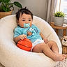 Mason is registered to the contest to win money with this photo: baby, basketball, carpet, chair, child, cozy, curtains, cute, diaper, furniture, indoor, pacifier, plant, plush_chair, potted_plant, relaxed, smiling_toy, teddy_bear, toddler, toy