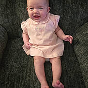 Tessa is registered to the contest to win money with this photo: baby, child, infant, smile, pink_dress, sitting, chair, cushion, happy, cute, portrait, indoors, person, young, skin, face, head, legs, feet, furniture