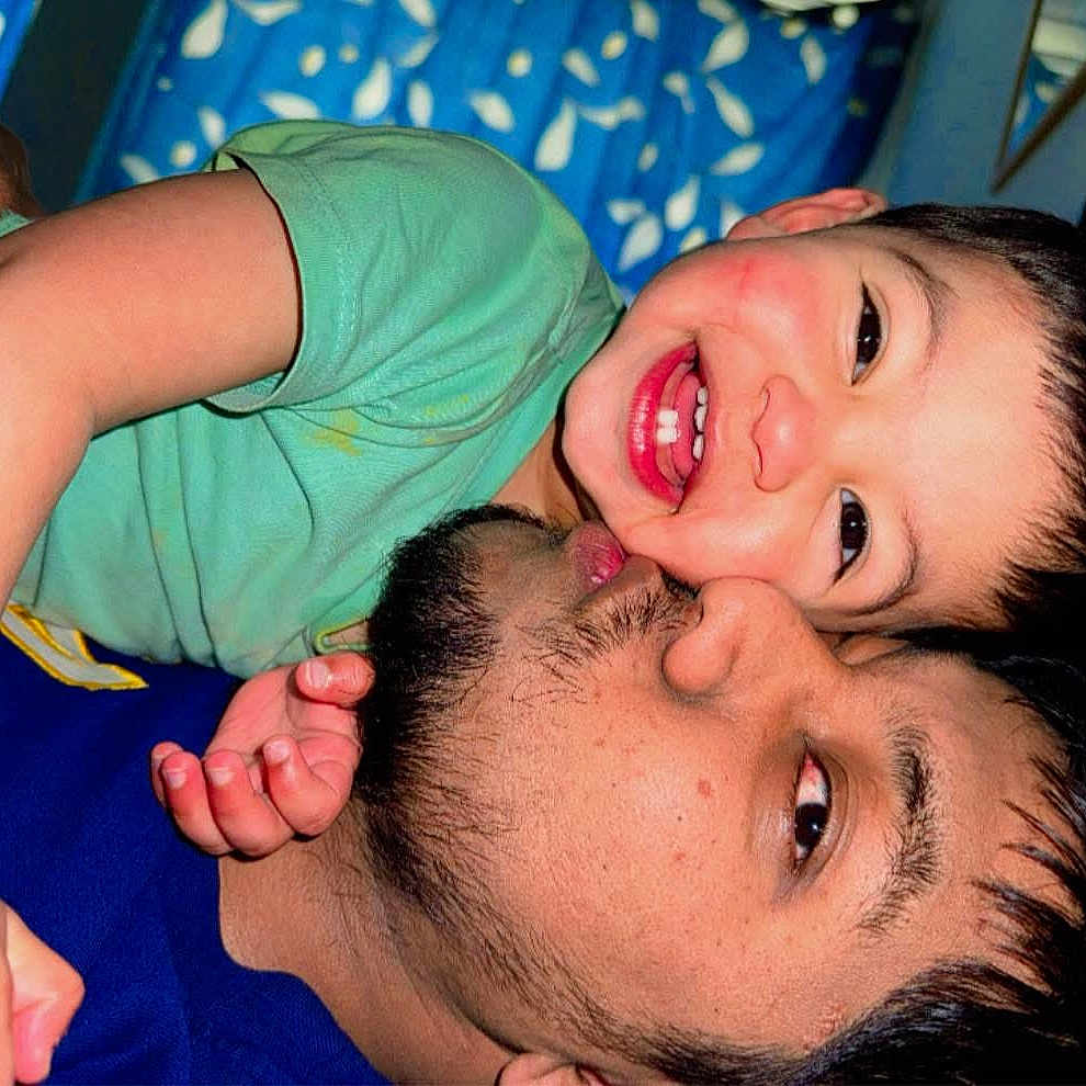 Zayan Ibne Ali is registered to the contest to win money with this photo: adult, affection, beard, blue_background, casual, child, closeup, face, family, green_shirt, happy, head, hug, indoor, joy, love, person, playful, skin, smile