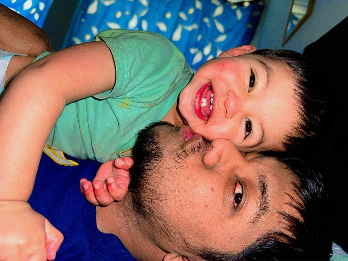 Zayan Ibne Ali is registered to the contest to win money with this photo: adult, affection, beard, blue_background, casual, child, closeup, face, family, green_shirt, happy, head, hug, indoor, joy, love, person, playful, skin, smile