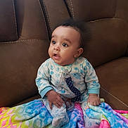 Kvion is registered to the contest to win money with this photo: baby, blanket, brown, child, clip, colorful, comfort, couch, cute, expression, face, foot, hand, indoors, infant, pacifier, pajamas, rainbow, sitting, soft