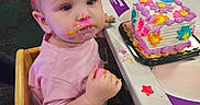 Kyra joined the competition — help win amazing prizes! birthday, cake, celebration, child, colorful, family, food, frosting, hand, happy, headband, high_chair, indoor, messy_face, party, person, pink_shirt, seat, table, toddler