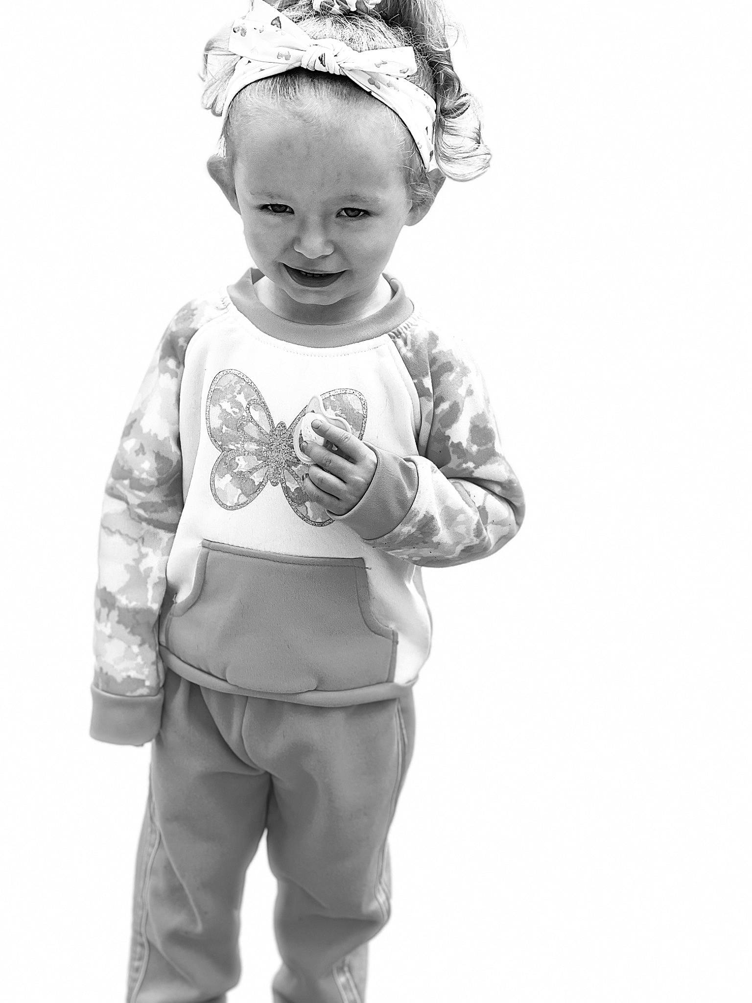 Ava joined the competition — help win amazing prizes! baby, baby_toddler_clothing, child, face, gesture, happy, head, headgear, headpiece, joy, monochrome, monochrome_photography, pattern, person, personal_protective_equipment, sleeve, smile, standing, style, t_shirt