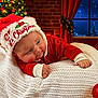 baby, infant, christmas, holiday, festive, santa_hat, red_clothing, blanket, cozy, fireplace, christmas_tree, lights, winter, night, window, curious, cute, indoors, celebration, smiling