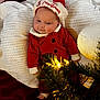 baby, infant, christmas, holiday, santa_hat, red_clothing, blanket, knitted, decorations, ornaments, christmas_tree, lights, festive, cute, smiling, indoors, holiday_season, celebration, cozy, portrait