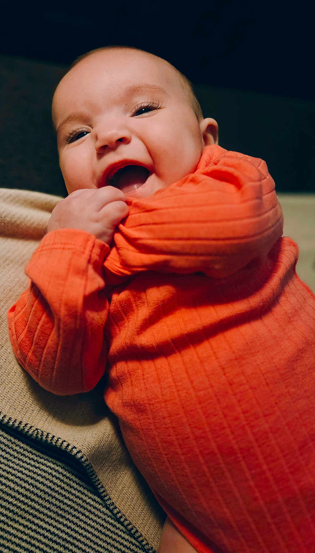 Maggie is registered to the contest to win money with this photo: baby, child, orange_clothing, smiling, happy, cute, portrait, infant, sleeve, grip, blanket, cozy, closeup, face, skin, eyelashes, mouth, indoor, person, joyful