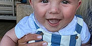 Teddy is registered to the contest to win money with this photo: baby, background, blue_striped_overall, cafe, casual_clothing, child, closeup, face, fingernails, hand, happy, holding, indoor, people, person, portrait, skin, smiling, white_shirt, wooden_chair