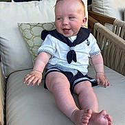 Teddy is registered to the contest to win money with this photo: baby, chair, child, clothing, cushion, cute, decor, face, foot, furniture, hand, happy, indoor, infant, person, sailor_outfit, shorts, skin, sleeve, smiling