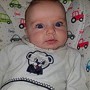 Emeline participe au concours pour gagner de l'argent avec cette photo : baby, infant, face, eyes, clothing, white_outfit, bear_embroidery, patterned_background, car_pattern, beep_text, cute, child, portrait, indoor, seat, expression, closeup, young, person, soft_lighting