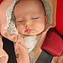 baby, sleeping, pink_jacket, fleece, hood, car_seat, seatbelt, red_padded_strap, infant, closeup, face, child, cozy, warm_clothing, nap, soft_texture, cute, peaceful, portrait, indoor