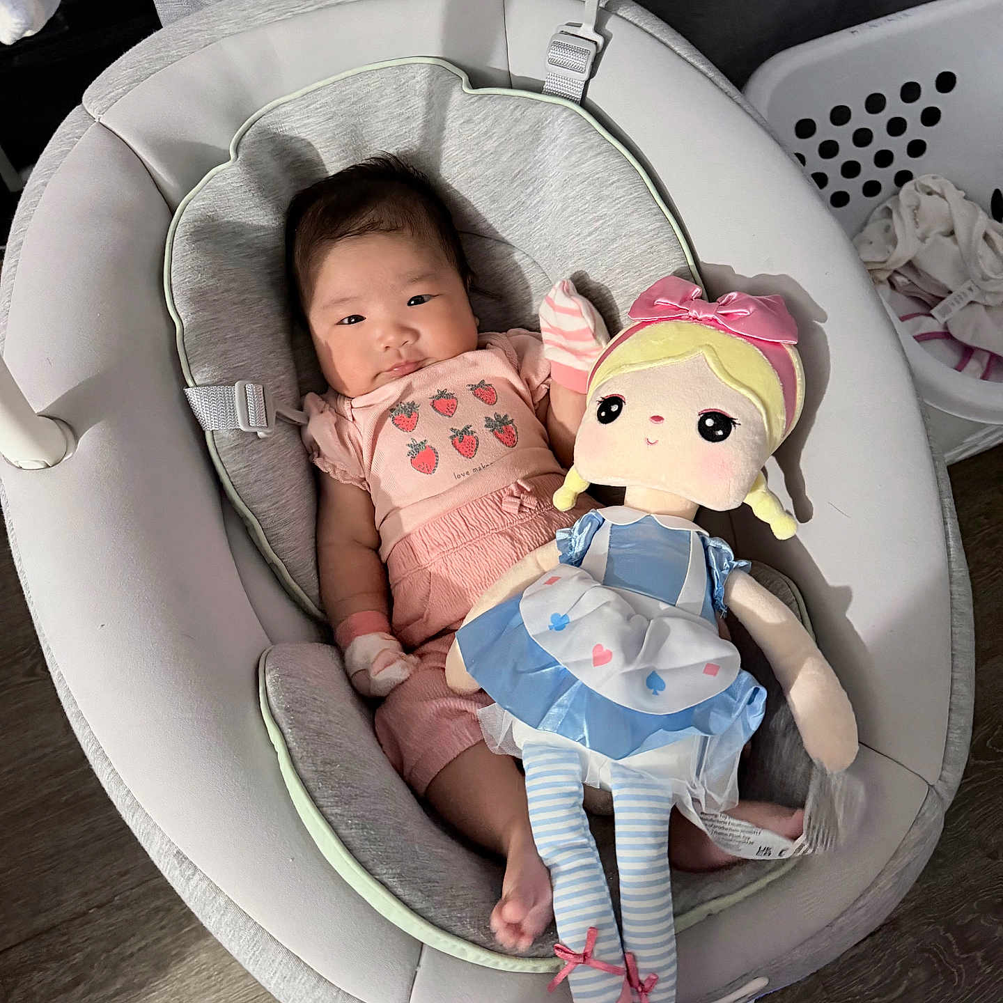 Alyana Kate is registered to the contest to win money with this photo: baby, infant, child, doll, plush_toy, rocker, baby_seat, pink_clothing, dress, bow, strawberries, sitting, lying_down, indoors, nursery, laundry_basket, wood_floor, curtain, portrait, smiling