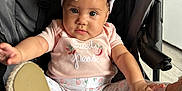 Hermoni is registered to the contest to win money with this photo: baby, infant, child, stroller, pink_clothing, headband, bow, cute, playful, reaching, legs, footwear, indoor, person, face, expression, curious, seat, fabric, soft_lighting