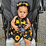 Hermoni is registered to the contest to win money with this photo: toddler, child, stroller, sunflower_dress, headband, curly_hair, outdoor, pavement, straps, footwear_free, serious_expression, baby, summer_clothing, sitting, person, cute, fashion, infant, seat, bright_colors