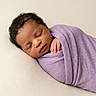 newborn, baby, sleeping, portrait, swaddled, lavender_wrap, infant, peaceful, cozy, close_up, face, curly_hair, closed_eyes, hand, blanket, soft_lighting, cream_background, indoors, photography, resting