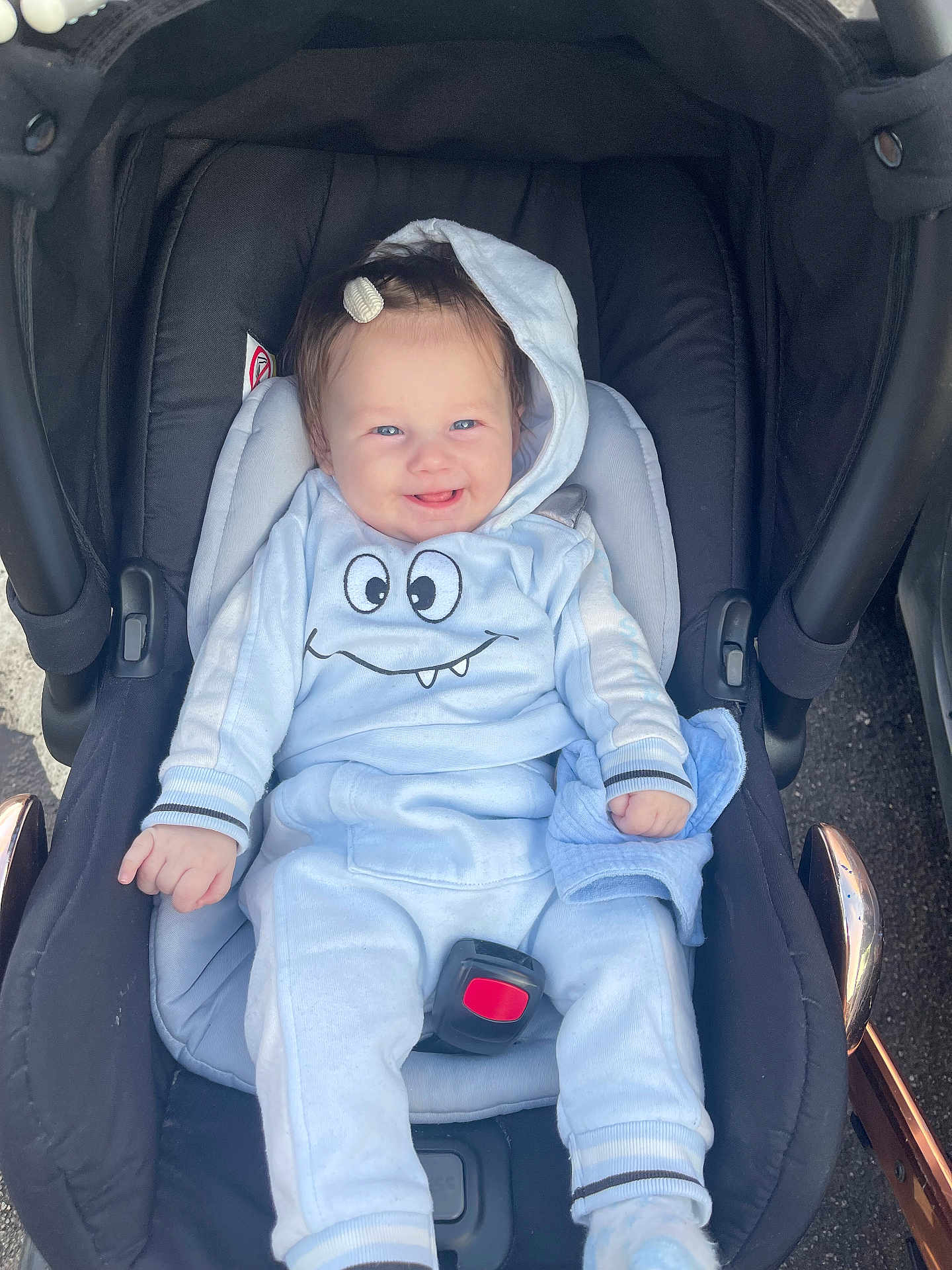 Elizabeth is registered to the contest to win money with this photo: baby, car_seat, child, smiling, blue_clothing, hoodie, hair_clip, infant, cute, happy, seatbelt, outdoor, person, young_child, playful, baby_clothes, sitting, light_blue, face, toddler