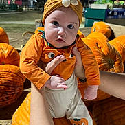 Michaela Rayne is registered to the contest to win money with this photo: baby, child, pumpkin, halloween, costume, orange, headband, flower, infant, outdoor, night, portrait, cute, wide_eyed, being_held, arms, fall, autumn, farm, festive