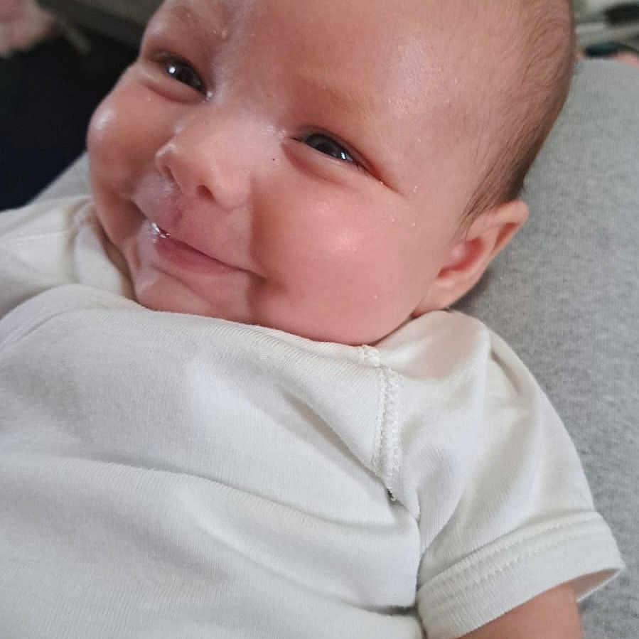 Ange participe au concours pour gagner de l'argent avec cette photo : baby, baby_garment, cheek, child, close_up, cute, expression, face, head, human, indoor, infant, newborn, person, portrait, skin, smiling, soft_light, white_clothing, young_child