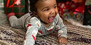 Kamran is registered to the contest to win money with this photo: baby, blurred_background, carpet, celebration, child, christmas_tree, crawling, cute, decorations, festive, happy, holiday, home, indoors, infant, joyful, pajamas, presents, rug, smiling