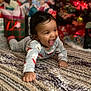 baby, blurred_background, carpet, celebration, child, christmas_tree, crawling, cute, decorations, festive, happy, holiday, home, indoors, infant, joyful, pajamas, presents, rug, smiling