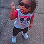 toddler, child, sunglasses, mickey_mouse, legend, shirt, white_shoes, sidewalk, concrete, curly_hair, standing, casual_clothing, outdoor, person, young_child, fashion, playful, cute, expression, hand_gesture