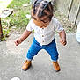 toddler, child, outdoor, standing, braided_hair, white_shirt, blue_pants, boots, concrete, grass, brick_wall, sign, twelve_months, baby, young_child, casual_clothing, daylight, portrait, person, looking_down