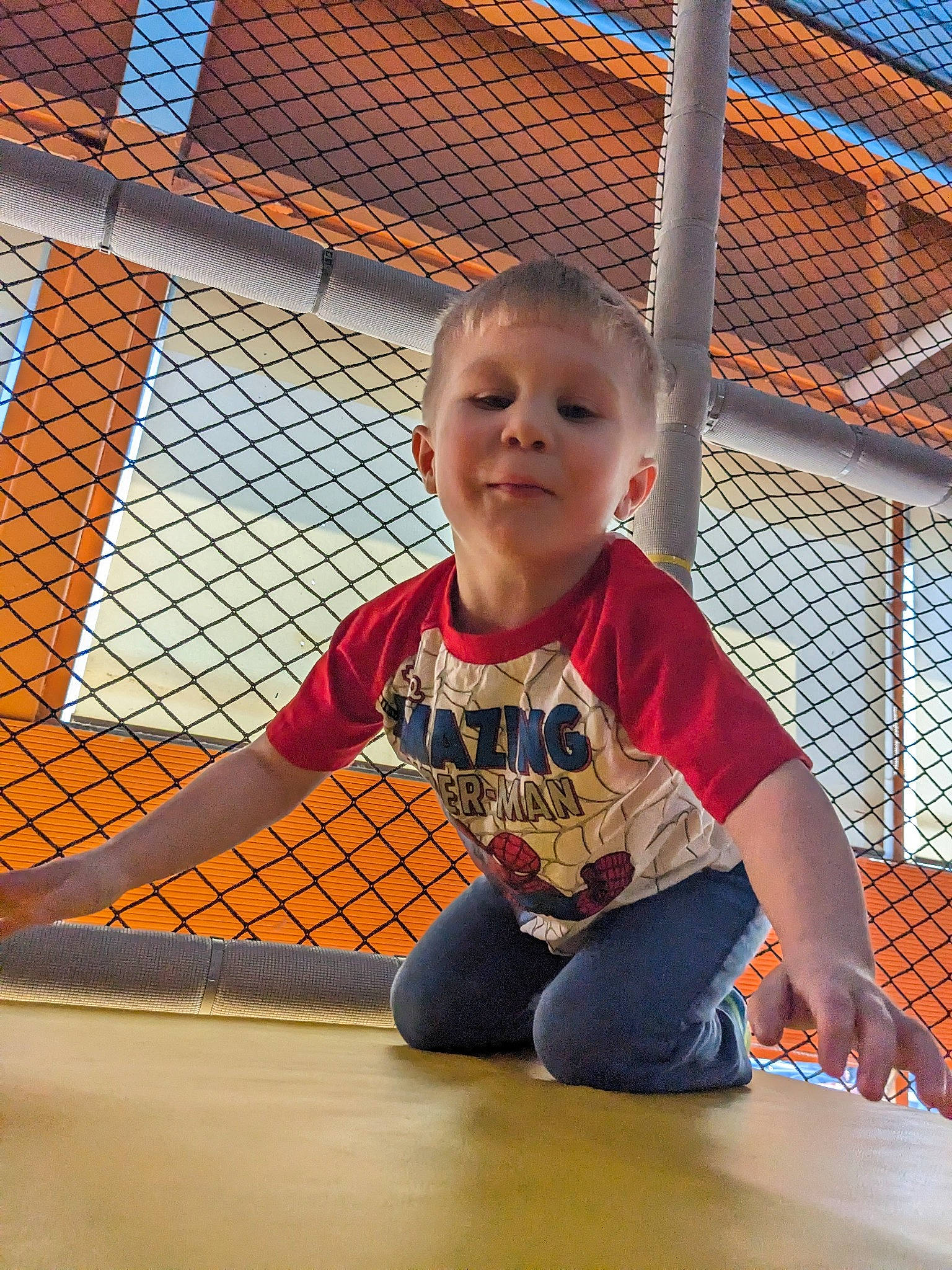 Jaxson is registered to the contest to win money with this photo: baby_toddler_clothing, child, city, flooring, fun, leg, leisure, mesh, net, orange, pattern, person, play, recreation, sitting, sleeve, smile, t_shirt, toddler, vacation