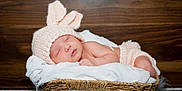 Leilani joined the competition — help win amazing prizes! baby, basket, bunny_ears, child, cozy, cute, headwear, indoors, infant, knitted_hat, newborn, peaceful, portrait, resting, sleeping, small, soft_fabric, wearing_clothes, white_blanket, wooden_background