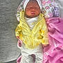 baby, sleeping, infant, yellow_jacket, white_pants, headband, bow, blanket, pink_blanket, animal_print_pillow, pacifier, soft_toys, couch, cozy, resting, indoors, cute, peaceful, newborn, child