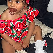 Myra participe au concours pour gagner de l'argent avec cette photo : toddler, child, pacifier, watermelon_pattern, headband, curly_hair, white_socks, white_sandals, couch, pillow, indoor, clothing, sitting, cute, small_child, person, fashion, accessory, colorful, portrait