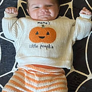 Dante is registered to the contest to win money with this photo: baby, infant, child, portrait, lying_down, smiling,  halloween, pumpkin, sweater, striped_pants, socks, blanket, star_pattern, moon, bat, indoor, close_up, face, happy, costume