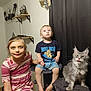 child, children, cat, cat_tree, indoor, curtain, hat, shelf, furniture, smile, tongue_out, shorts, tshirt, patterned_clothing, hair, barefoot, playful, pet, family, home