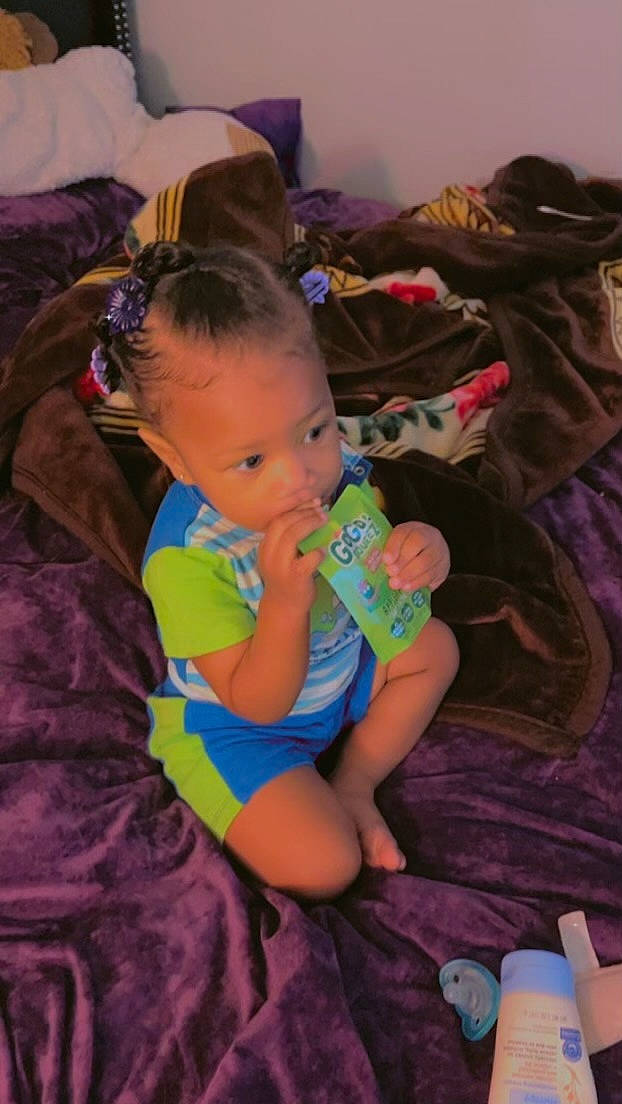 Taliyah is registered to the contest to win money with this photo: baby, baby_products, baby_toddler_clothing, cheek, child, comfort, ear, event, eye, fun, iris, lap, nail, person, play, purple, room, sitting, skin, t_shirt