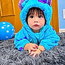 baby, balloon, blue, bracelet, child, close_up, costume, cute, hands, home, hoodie, indoor, large_eyes, portrait, purple, rug, serious_expression, sitting, toddler, wooden_door