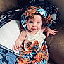 baby, infant, toddler, child, blue_eyes, smile, hat, dress, tropical_pattern, leaves, couch, blanket, pillow, cozy, portrait, barefoot, hand, living_room, skin, cute