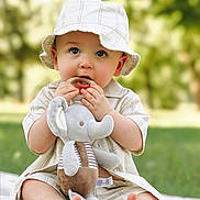 Josiah is registered to the contest to win money with this photo: baby, child, hat, plush_toy, elephant_toy, outdoor, grass, blanket, cute, curious, sitting, soft_toy, clothing, toes, young_child, nature, portrait, summer, innocent, playful