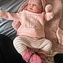 apparel, baby, blanket, child, cozy, cute, face, headband, indoor, infant, knitted_clothing, lying_down, mittens, newborn, pink, portrait, sleepwear, soft_texture, striped_pants, warm