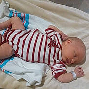Aron is registered to the contest to win money with this photo: baby, sleeping, onesie, striped_clothing, blanket, towel, infant, peaceful, resting, bed, soft, newborn, person, skin, head, arm, hand, foot, lying_down, indoors