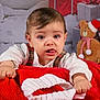toddler, child, baby, face, tongue, blanket, red, white, knitted, christmas, holiday, presents, gift, decorations, teddy_bear, santa_hat, plaid, shirt, indoor, portrait