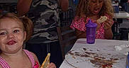 Mika Rayne is registered to the contest to win money with this photo: children, toddler, kids, snacks, eating, cake, sandwich, birthday, party, table, restaurant, indoor, smiling, glasses, curly_hair, pink_dress, camouflage_shirt, purple_bottle, food, family