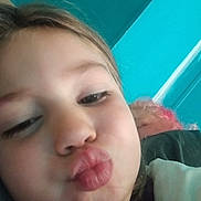 Mika Rayne is registered to the contest to win money with this photo: child, toddler, portrait, selfie, face, close_up, duck_face, pouting, young_person, blonde_hair, eyes, nose, lips, cheeks, indoor, turquoise_background, pink_object, casual, photography, safe