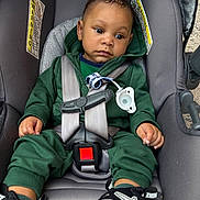 Maison is registered to the contest to win money with this photo: baby, child, car_seat, seatbelt, pacifier, green_clothing, hoodie, sneakers, nike, black_shoes, infant, sitting, safety, restraint, child_safety, portrait, indoors, cute, young_child, casual_clothing