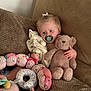Mya joined the competition — help win amazing prizes! toddler, child, pacifier, teddy_bear, blanket, plush_toys, couch, brown_couch, soft_texture, indoors, cute, infant, comfort, seated, toy_caterpillar, baby, relaxed, home, young_child, cozy
